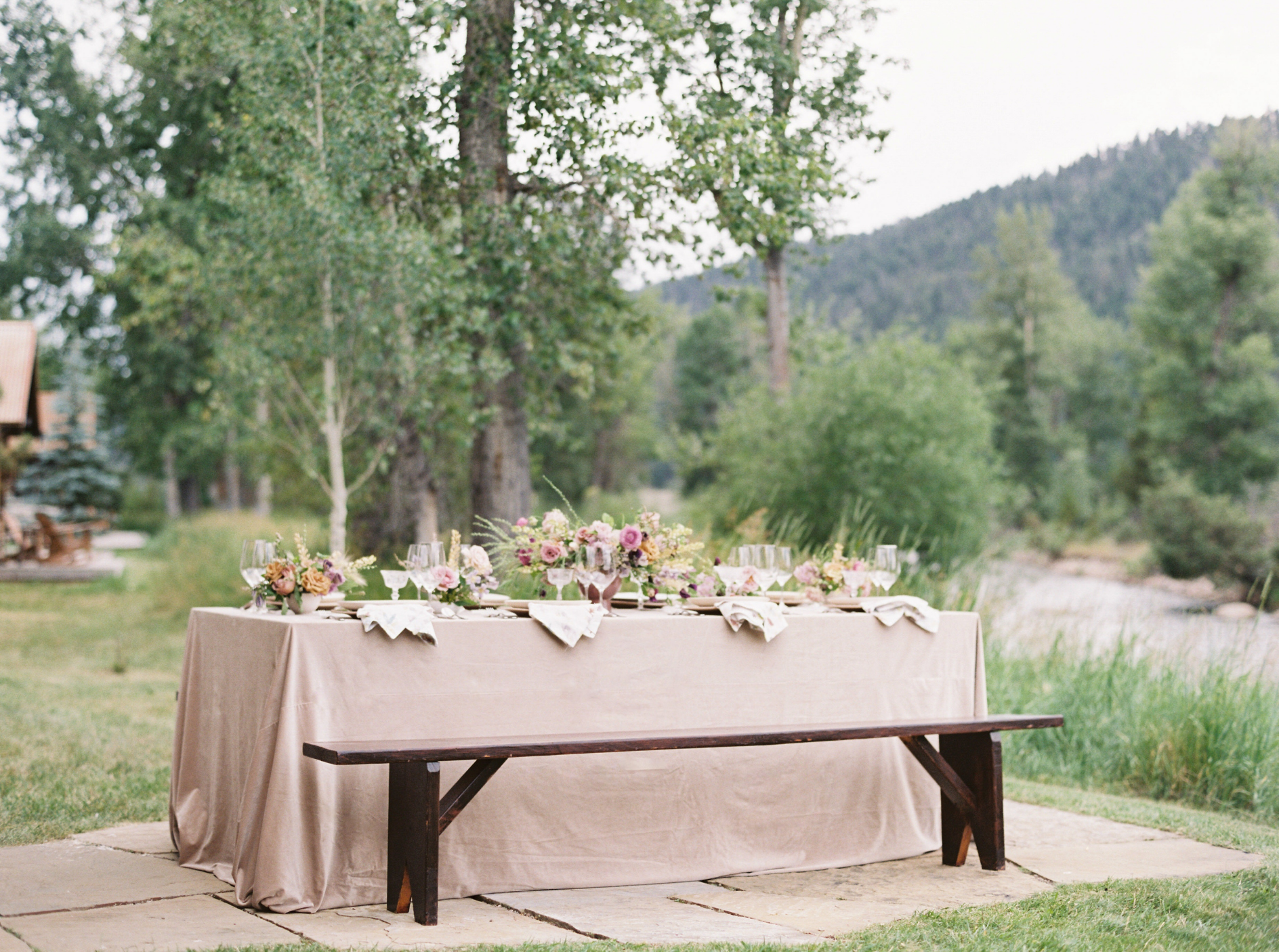 Intimate table setting covered in blush velvet with sprawling florals. Set beside a river. 